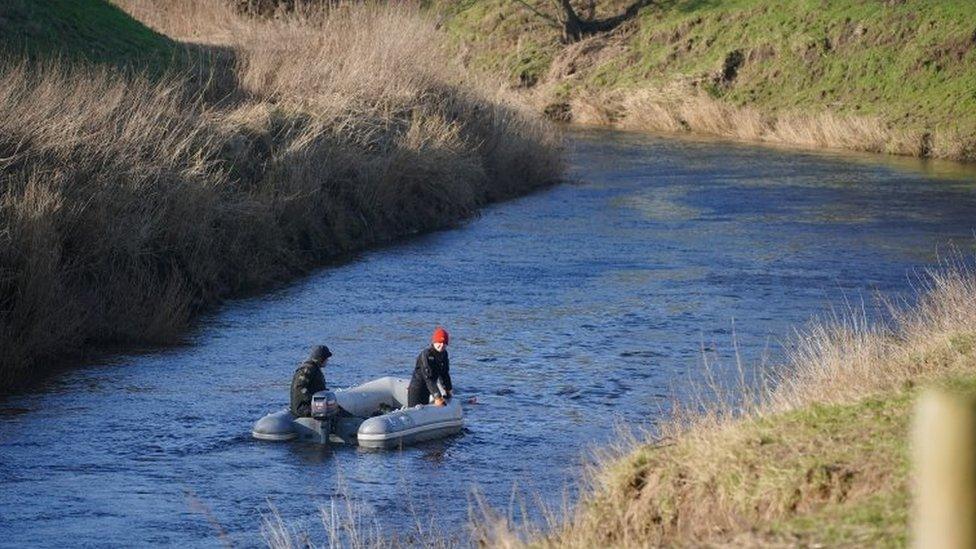 Specialist search officers drive a boat along the River Wyre