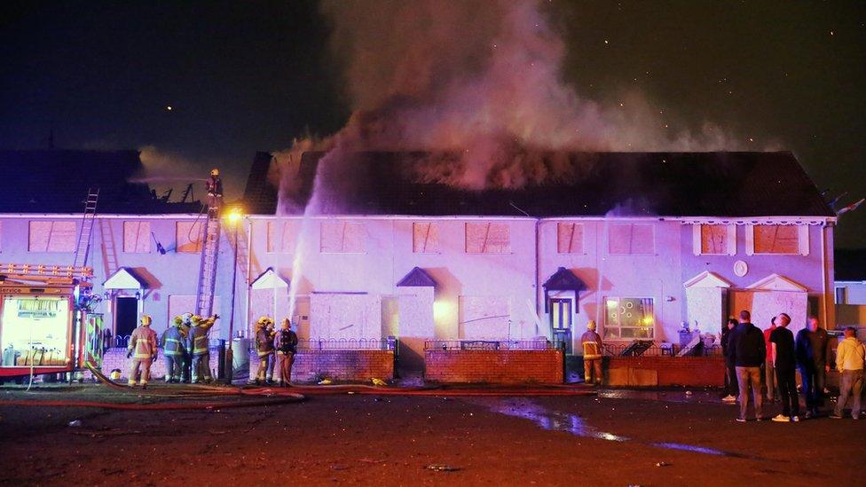 Firefighters work to put out fires in houses at Hopewell Square in Belfast's Shankill area