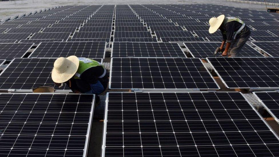 Workers at the world's largest floating solar power plant in a lake in Huainan