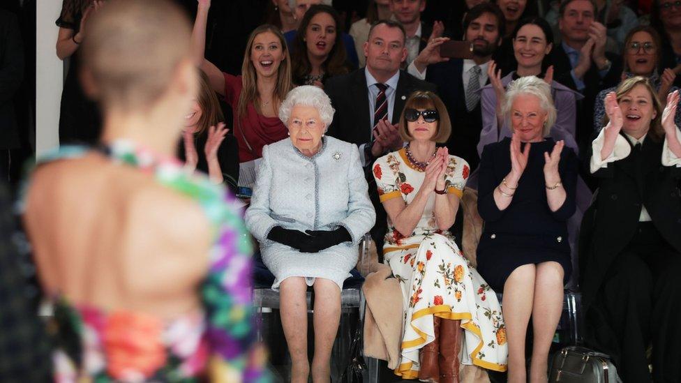 The Queen and Anna Wintour watch as a model walks the runway