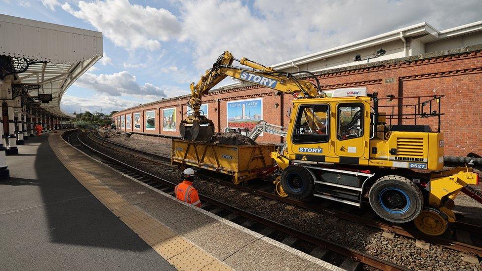 Digger on rails lifts rubble into skip