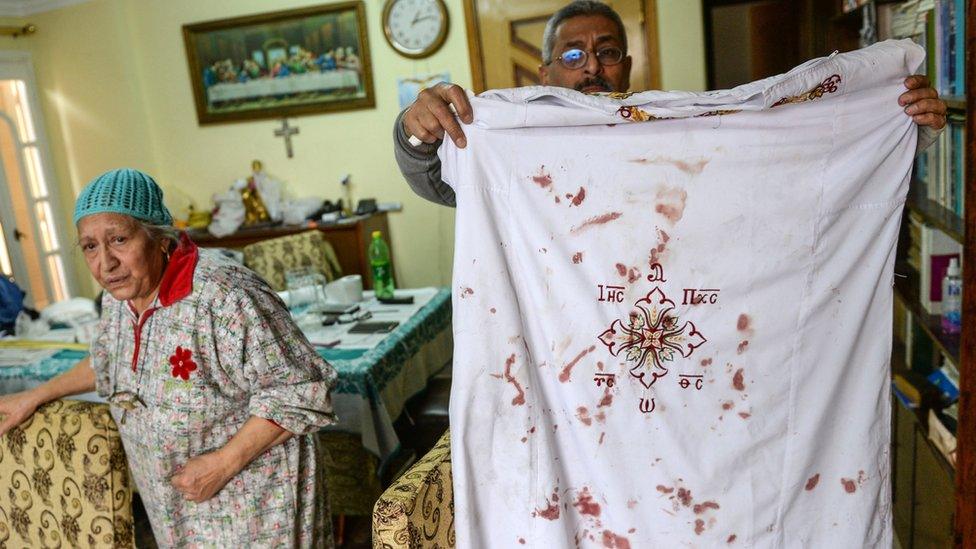 A man holds a Coptic clergy clothes with blood stains on them at Mar Girgis church after a bomb explosion