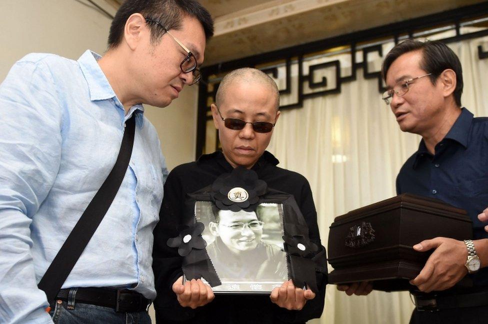 Liu Xiaobo's wife Liu Xia and his brother, Liu Xiaoguang, hold a portrait of Liu Xiaobo as they receive his ashes (R) in an urn at a funeral parlour in the Chinese city of Shenyang, Liaoning province, on 15 July, 2017.