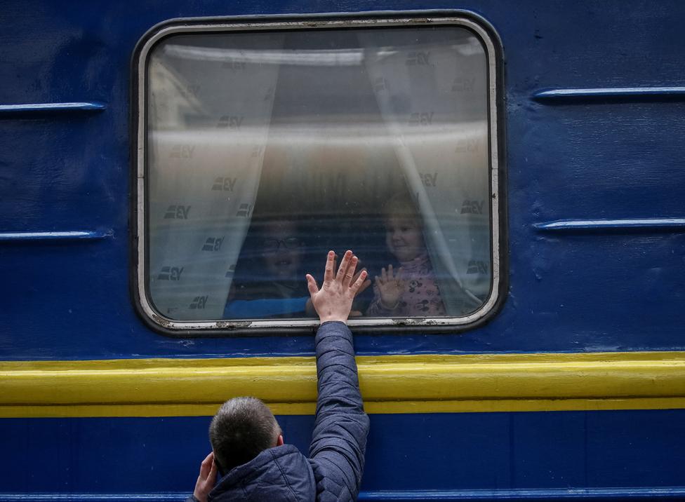 Children look out from an evacuation train from Kyiv to Lviv as they say goodbye to their father. Photo: 3 March 2022