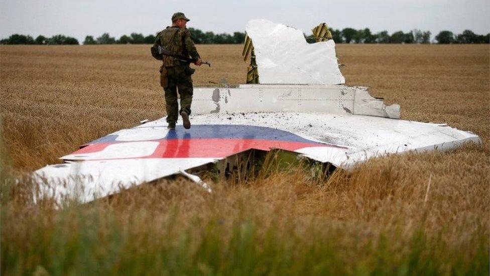 An armed pro-Russian separatist stands on part of the wreckage of the Malaysia Airlines Boeing 777 plane after it crashed near the settlement of Grabovo in the Donetsk region, July 17, 2014