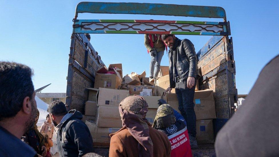 File photo showing Syrians receiving aid at a make-shift shelter near the opposition-held town of Jindayris (9 February 2023)