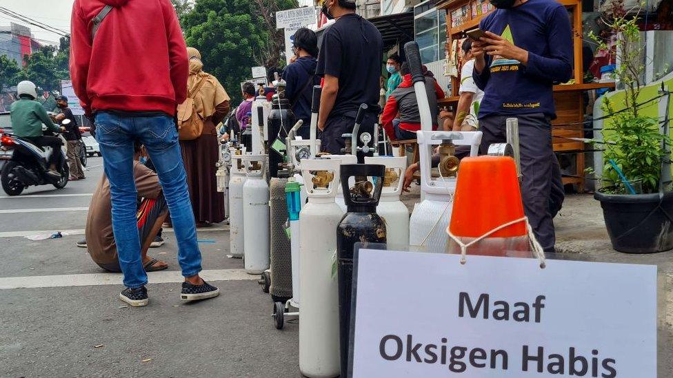 Signage that reads 'sorry, out of oxygen' is seen as people queue outside an oxygen refilling shop