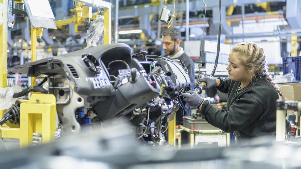 An apprentice engineer works on a car factory production