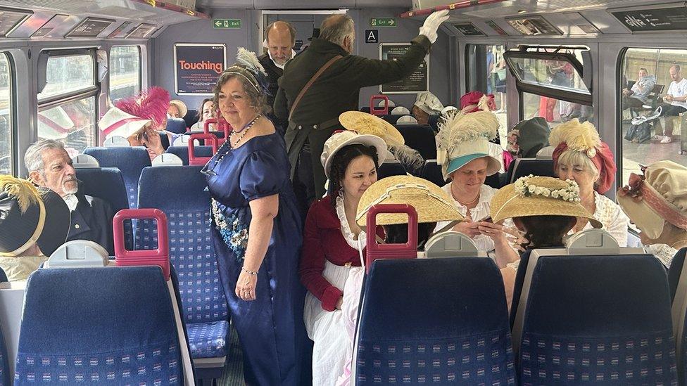 People in period dress on train