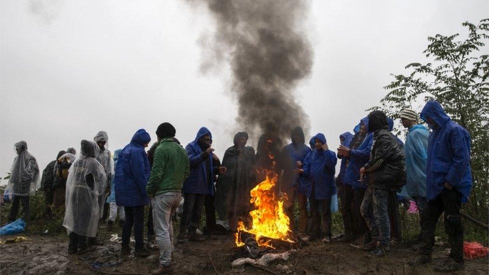 Migrants try to keep themselves warm at the Serbia-Croatia border, 19 October 2015