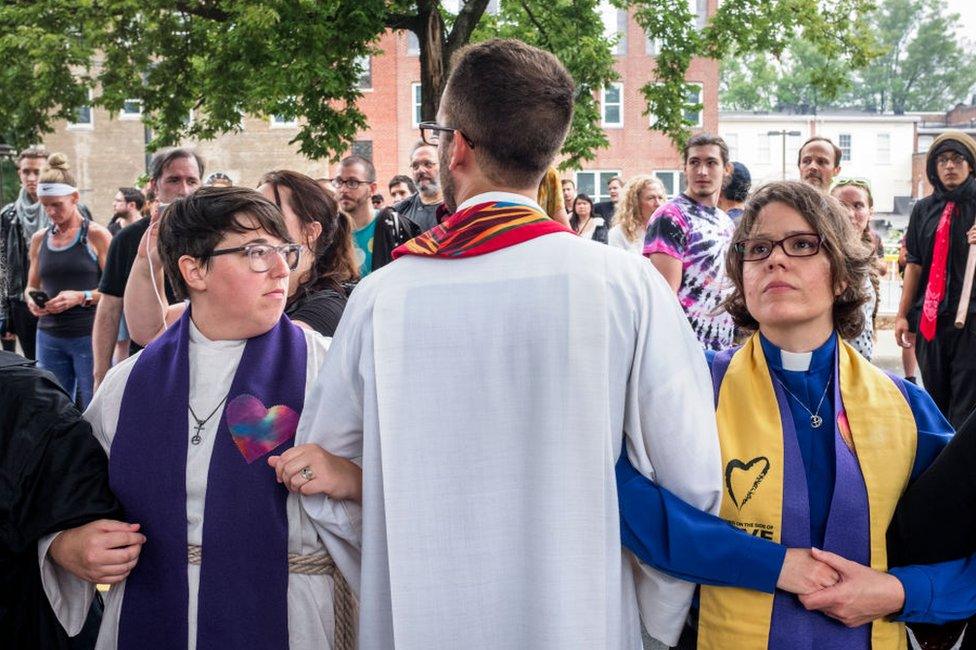 Rev Seth Wispelwey, centre, locks arms with other clergy members at the entrance to the park