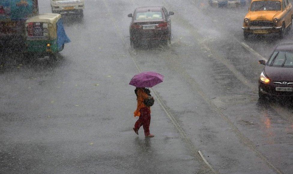 A woman tries to manage her umbrella between storm with heavy rain on street in Calcutta, eastern India, 23 May 2016.