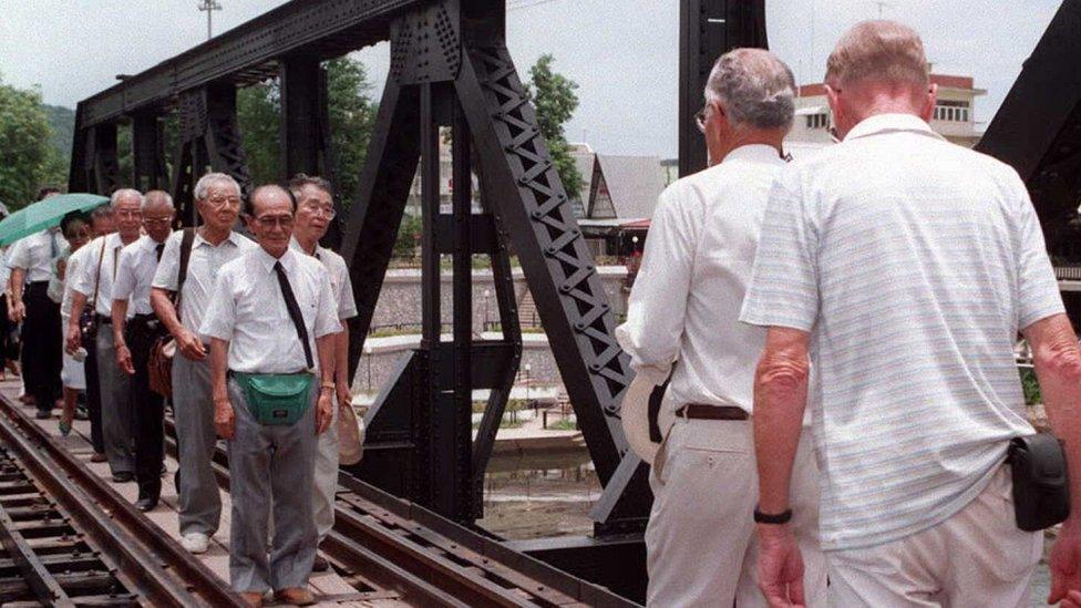 Two Australian former prisoners of war (R) march across the famous bridge over the River Kwai to meet with the Japanese lead group of war veterans 15 August in Kanchanaburi, western Thailand, to mark the 50th anniversary of the end of World War II