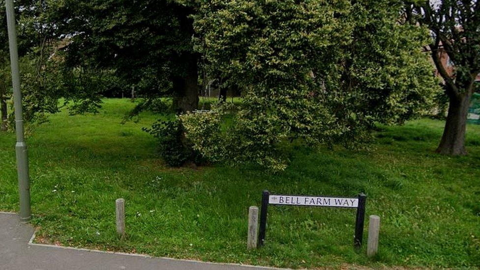 The Bell Farm Way road sign next to some trees