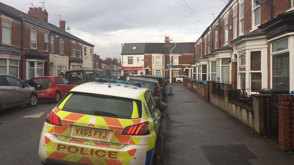 Police car down a residential street with terraced houses