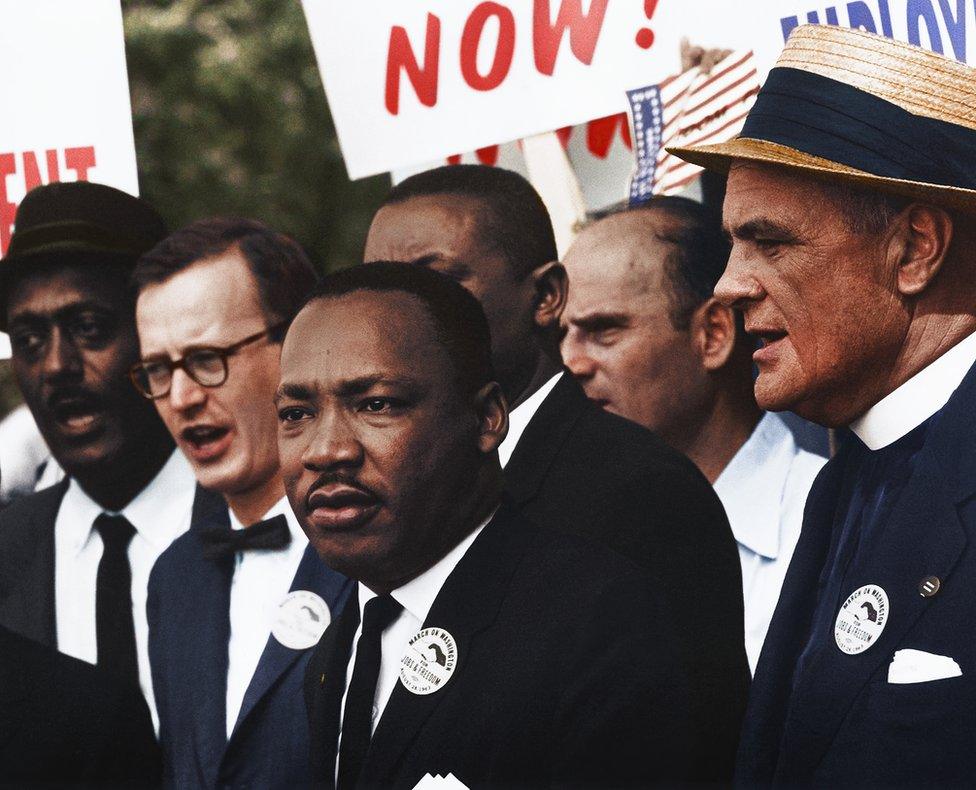 Dr. Martin Luther King stands with others at a march in a colourised photo