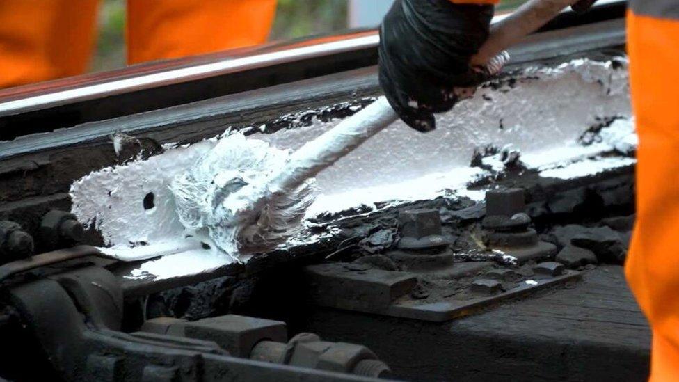 A Network Rail worker paints railways white