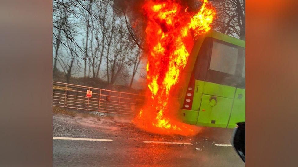 Image of a green bus which is on fire.