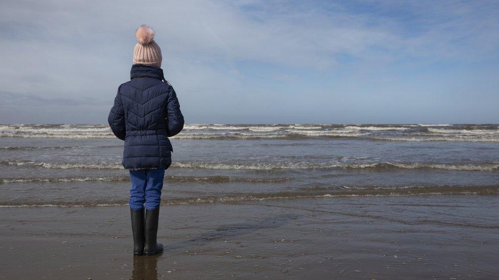 Anonymous young person looking out to sea