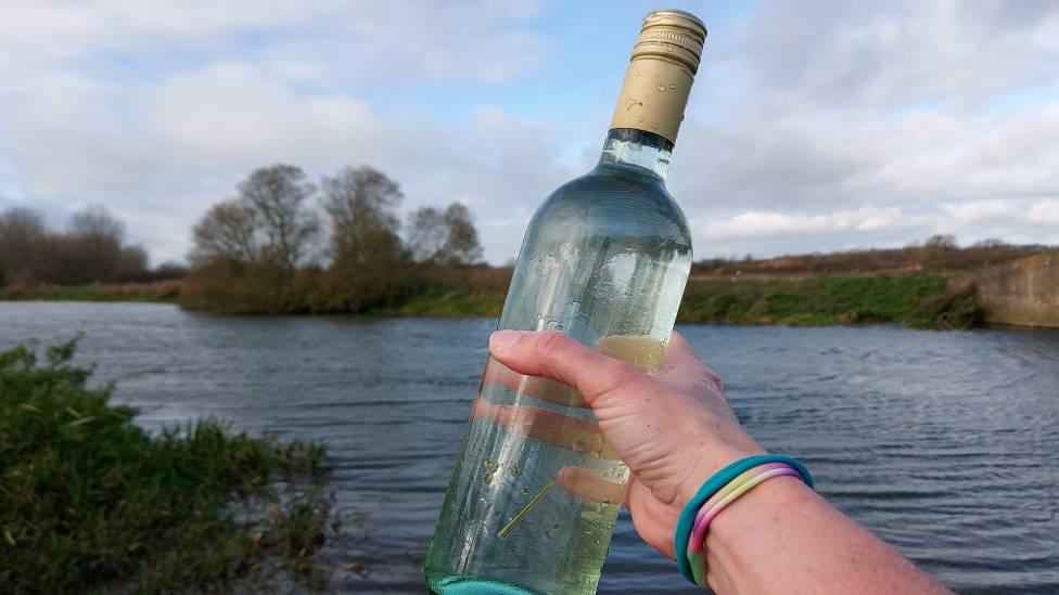 a swimmer brandishes a wine bottle full of water