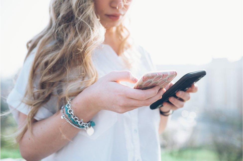 woman with two phones