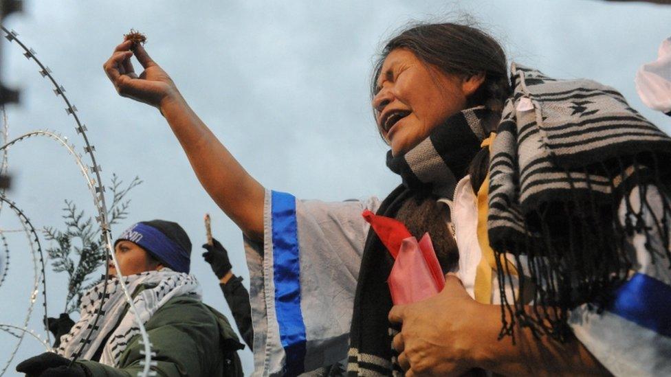 A Native American protester makes a ceremonial tobacco offering