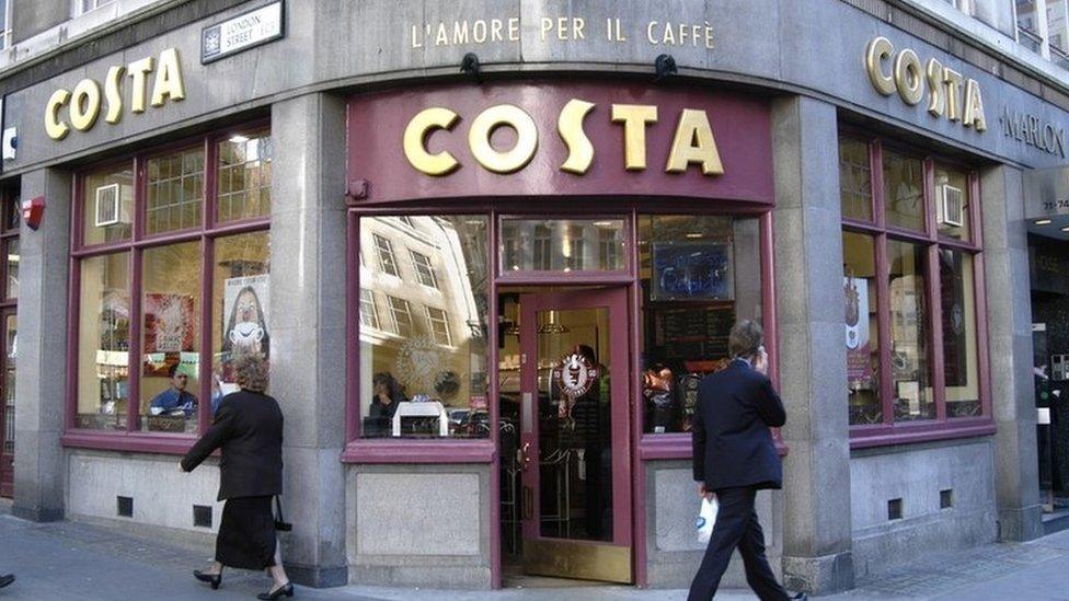 Customers walk past a Costa coffee branch in London
