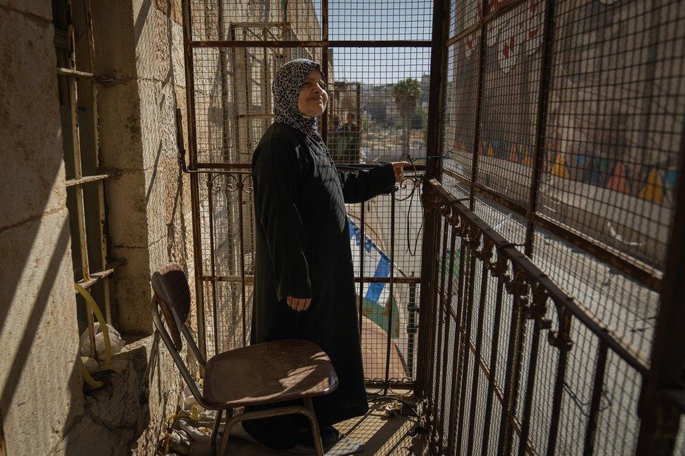 Zleekhah Mohtaseb on a typical Palestinian balcony on Shuhada Street, caged in to protect against stones.