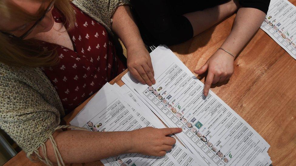 Staff at a count centre check ballot papers