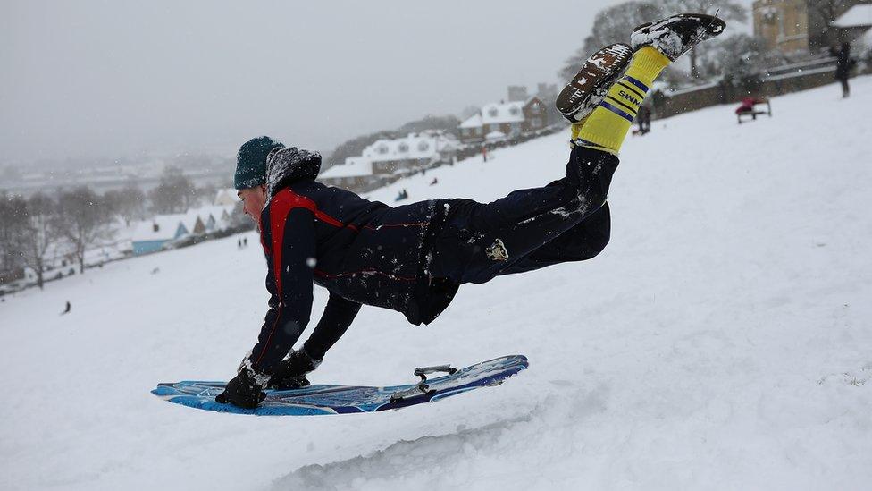 A man leaping onto a toboggan