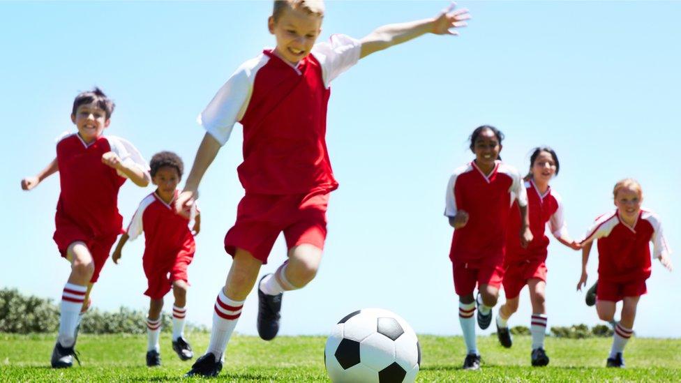 Girls and boys playing football together