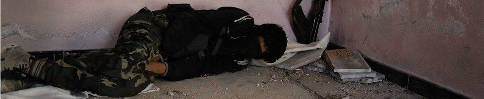 A Syrian rebel fighter from the Failaq al-Rahman brigade rests inside a building in the Ghouta region near Damascus, 28 February