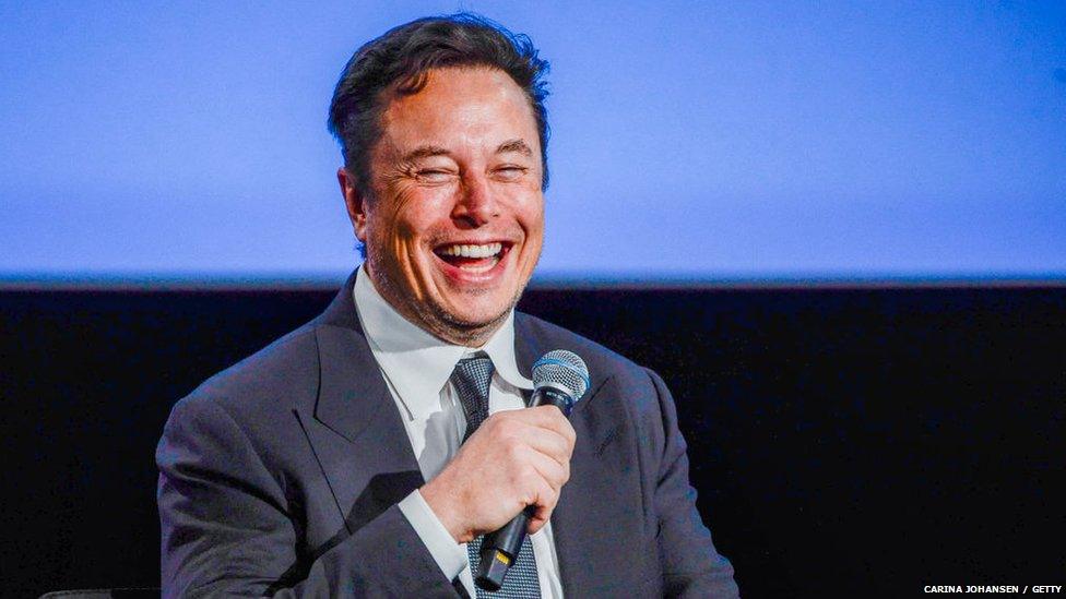 Elon Musk smiling with a microphone