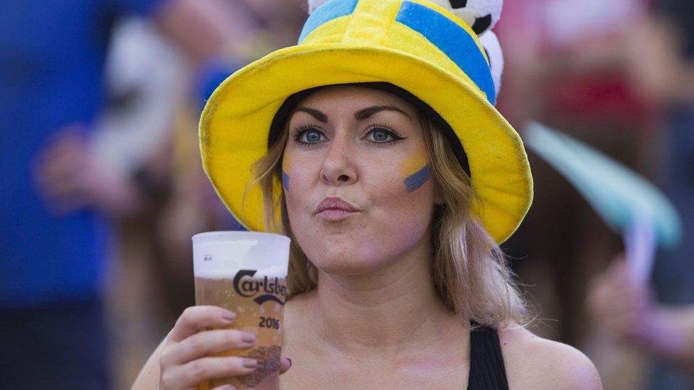 A Sweden fan drinks beer as she watches the Euro 2016 group E football match between Sweden and Belgium on a big screen