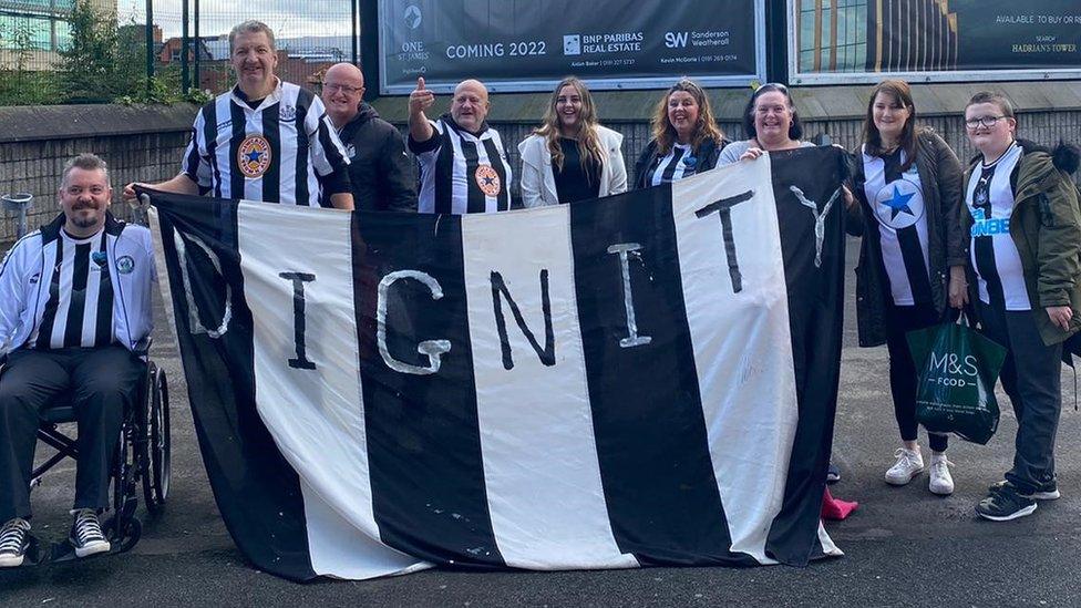 Fans from foodbank holding banner