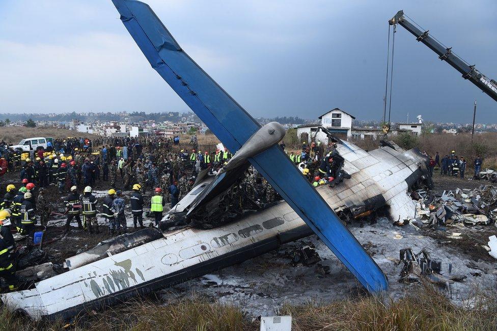 Nepali rescue workers gather around the debris of an airplane that crashed near the international airport in Kathmandu on March 12, 2018. At least 40 people were killed and 23 injured when a Bangladeshi plane crashed and burst into flames near Kathmandu airport on March 12, in the worst aviation disaster to hit Nepal in years. Officials said there were 71 people on board the US-Bangla Airlines plane from Dhaka when it crashed into a football field near the airport