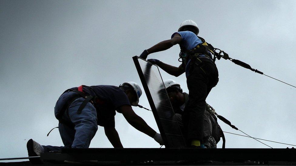 Workers put solar panels down during an installation May 3, 2106 in Washington, DC.