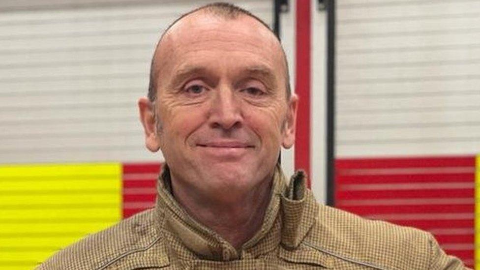 A man in fire uniform smiles at the camera