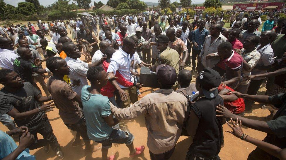 A Ugandan policeman struggles to keep hold of a box containing voting material in Ggaba, on the outskirts of Kampala