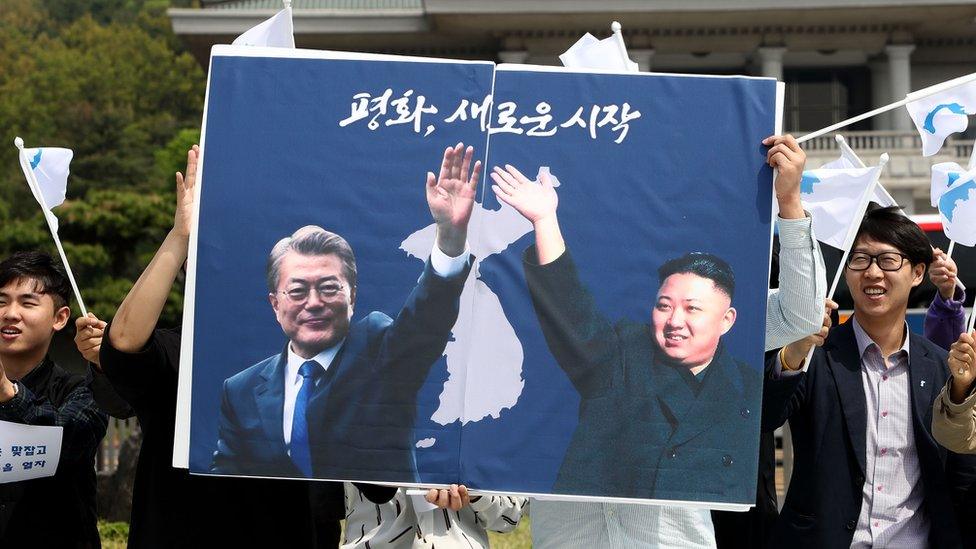 Students hold posters with pictures of South Korea"s President Moon Jae-in and North Korea"s leader Kim Jong Un during a pro-unification rally