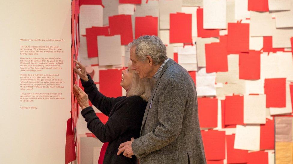 Two people looking at a wall of letters