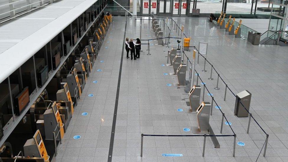 Three members of staff in an otherwise empty airport terminal