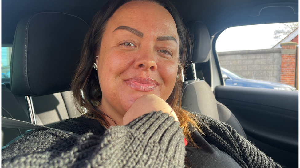 Woman with dark hair, sat in a car