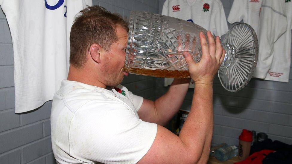 Rugby player drinking from a giant vase