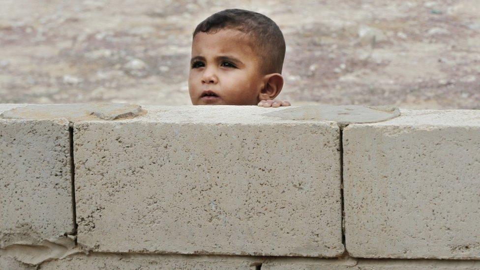 A Syrian boy peeks from behind a wall near a mobile clinic at a refugee camp in the southern town of Zahrani, south of the port city of Sidon, Lebanon