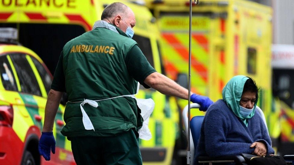 An NHS ambulance worker takes a patient in a wheelchair