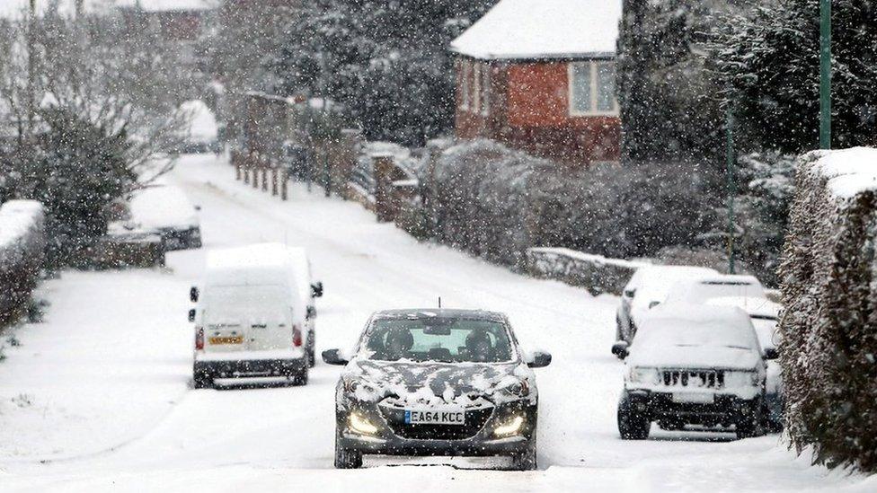 Cars driving down a snowy road