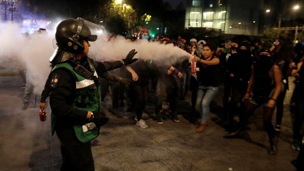 A demonstrator aims a fire extinguisher towards a police officer during a protest against femicide and violence against women, in Mexico City, Mexico, 25 November 25.