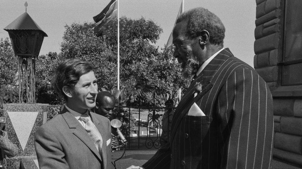 Black and white photo of King Charles shaking hands with Jomo Kenyatta.