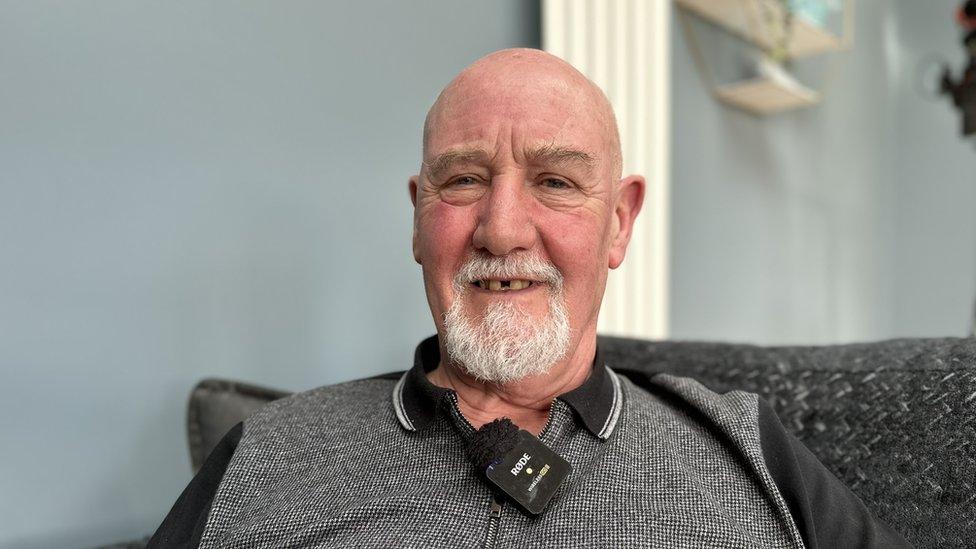 A man with a white beard smiles at the camera